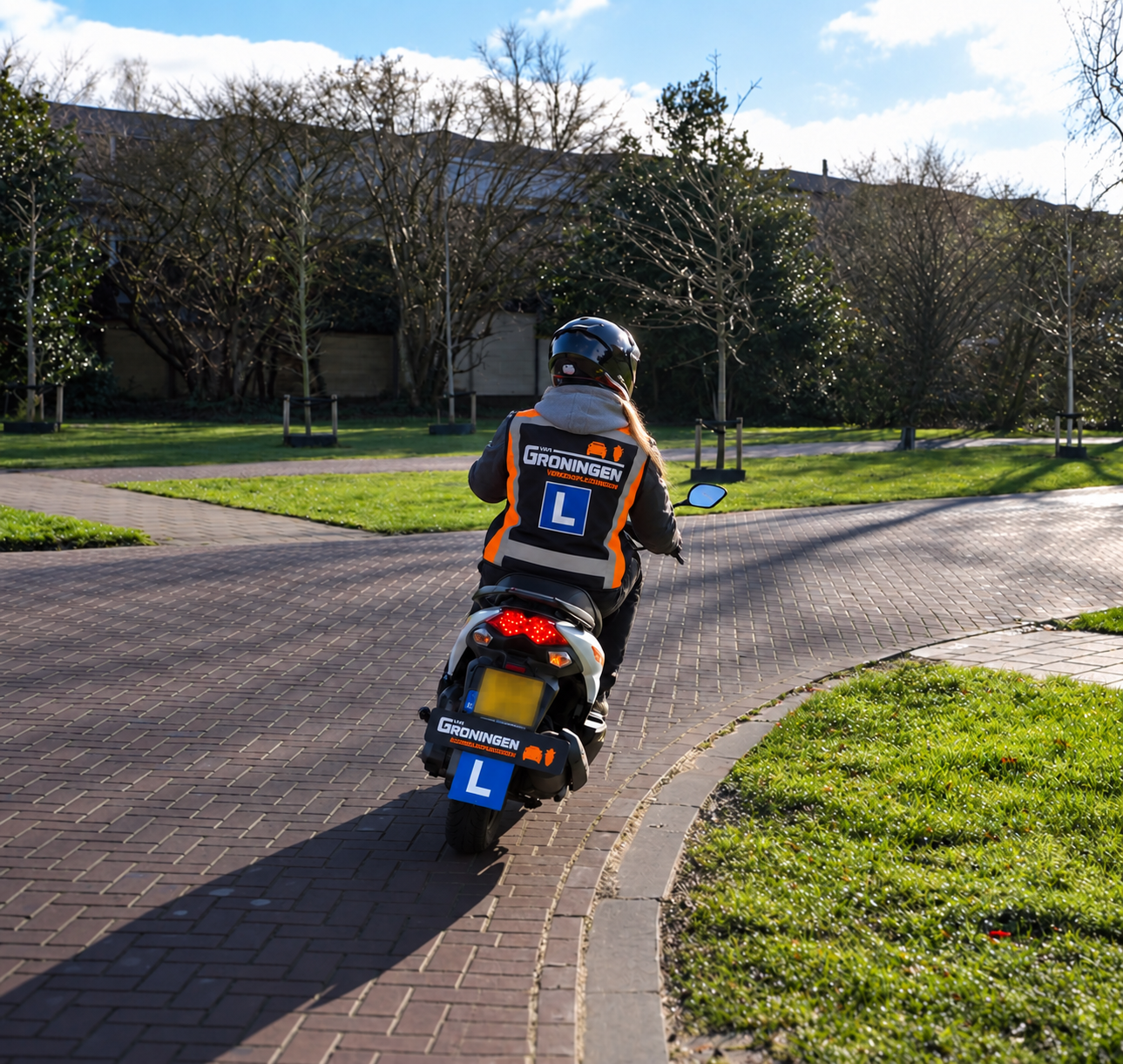 Bromfietsleerling met L-hesje en Van Groningen Verkeersopleidingen-vest tijdens de bromfietsopleiding