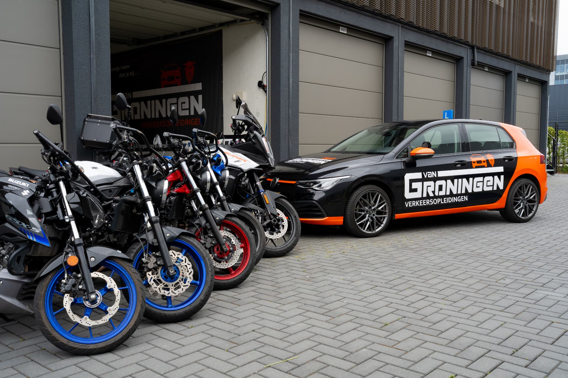 Lesmotoren en de zwart-oranje lesauto van Van Groningen Verkeersopleidingen bij de vestiging