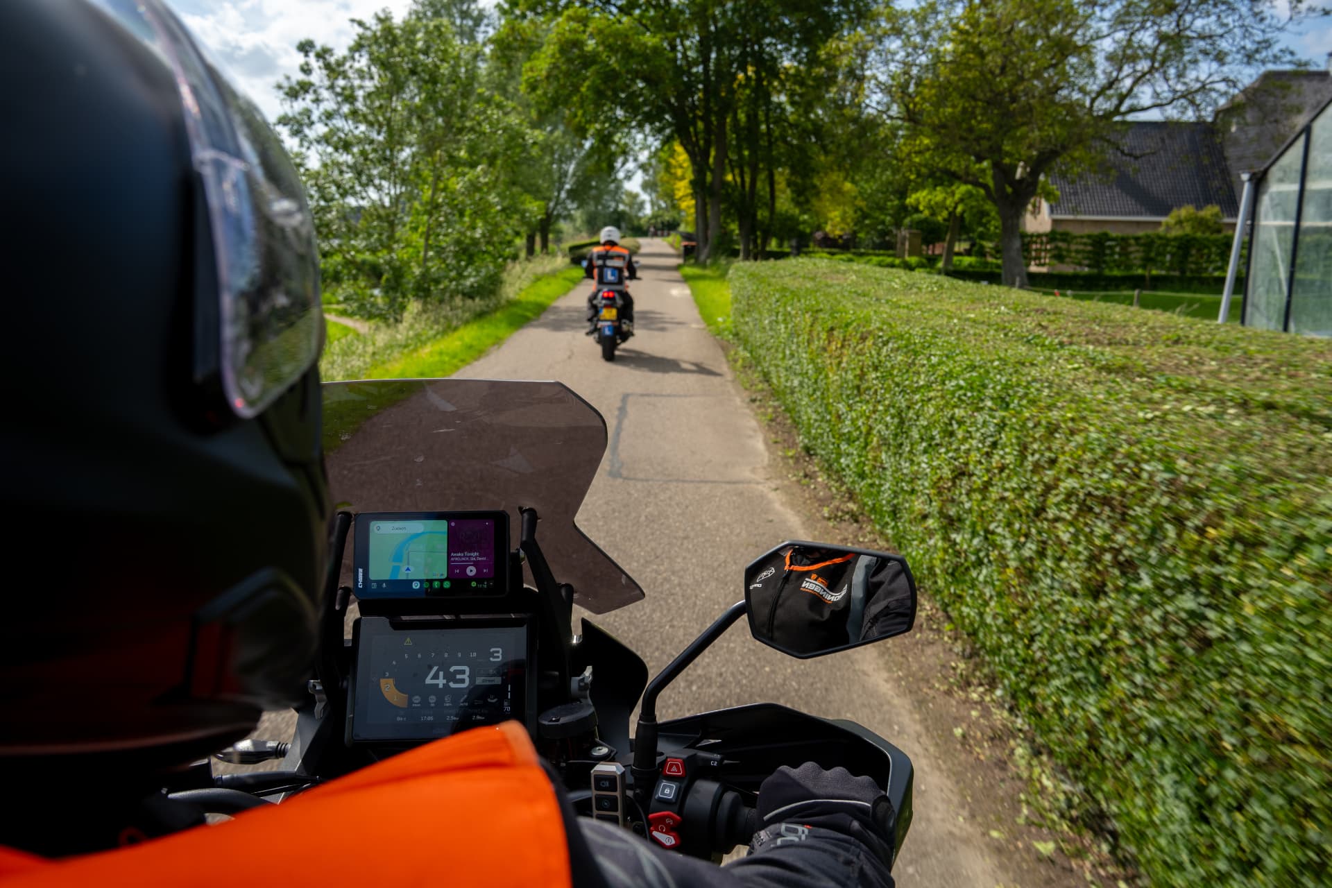 Zicht vanaf de instructeursmotor met de leerling vooruit op een landweg