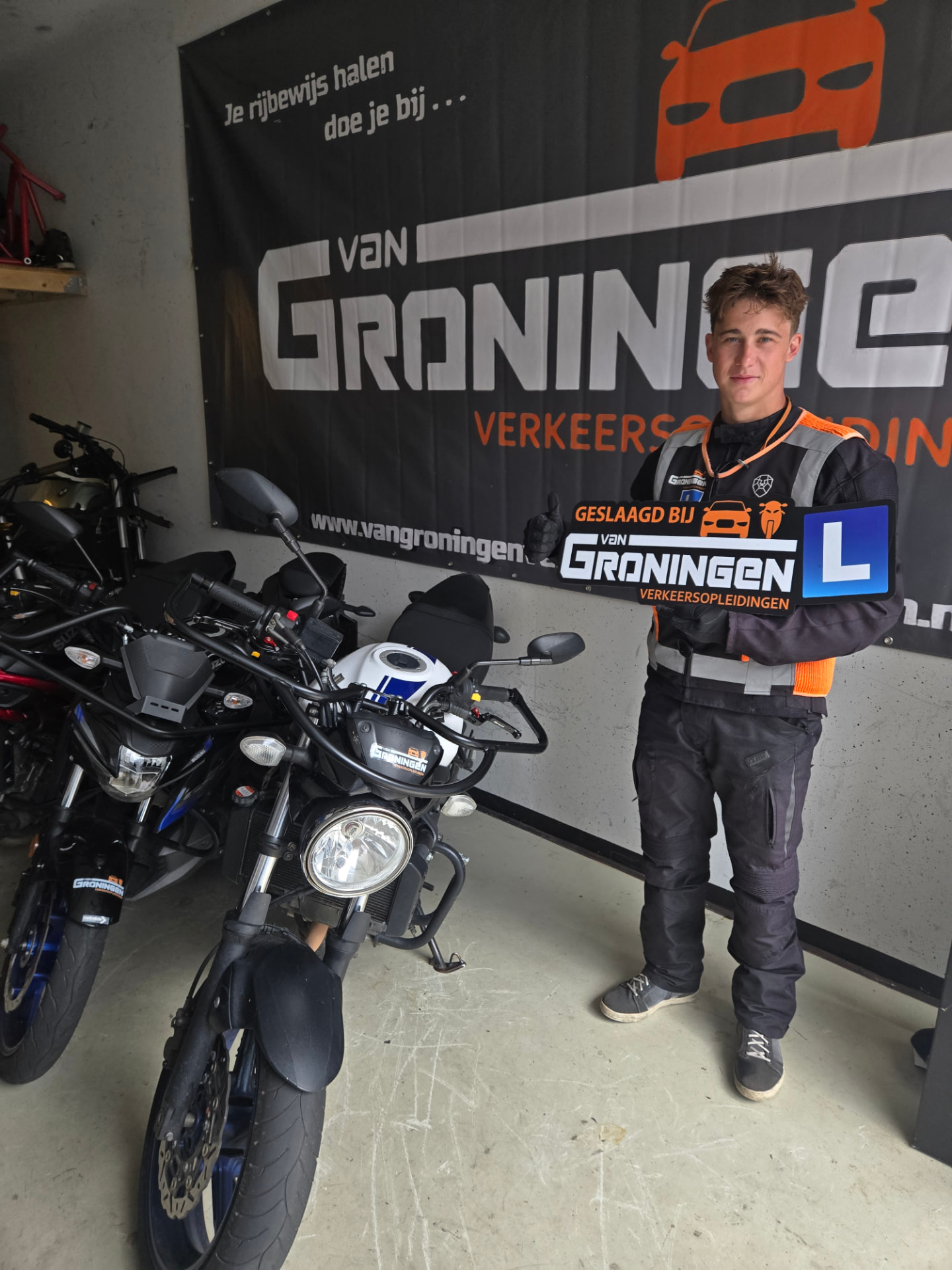 Geslaagde motorleerling naast de lesmotor bij de vestiging