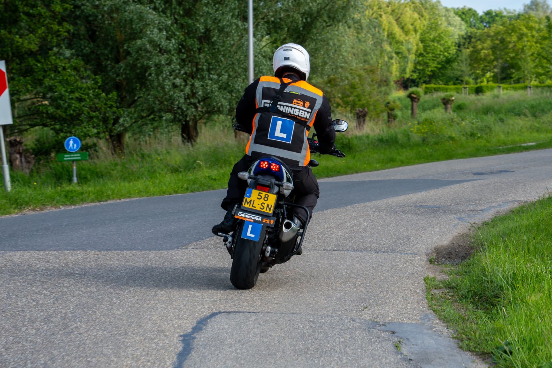 Motorleerling met L-hesje van Van Groningen Verkeersopleidingen tijdens motorrijles