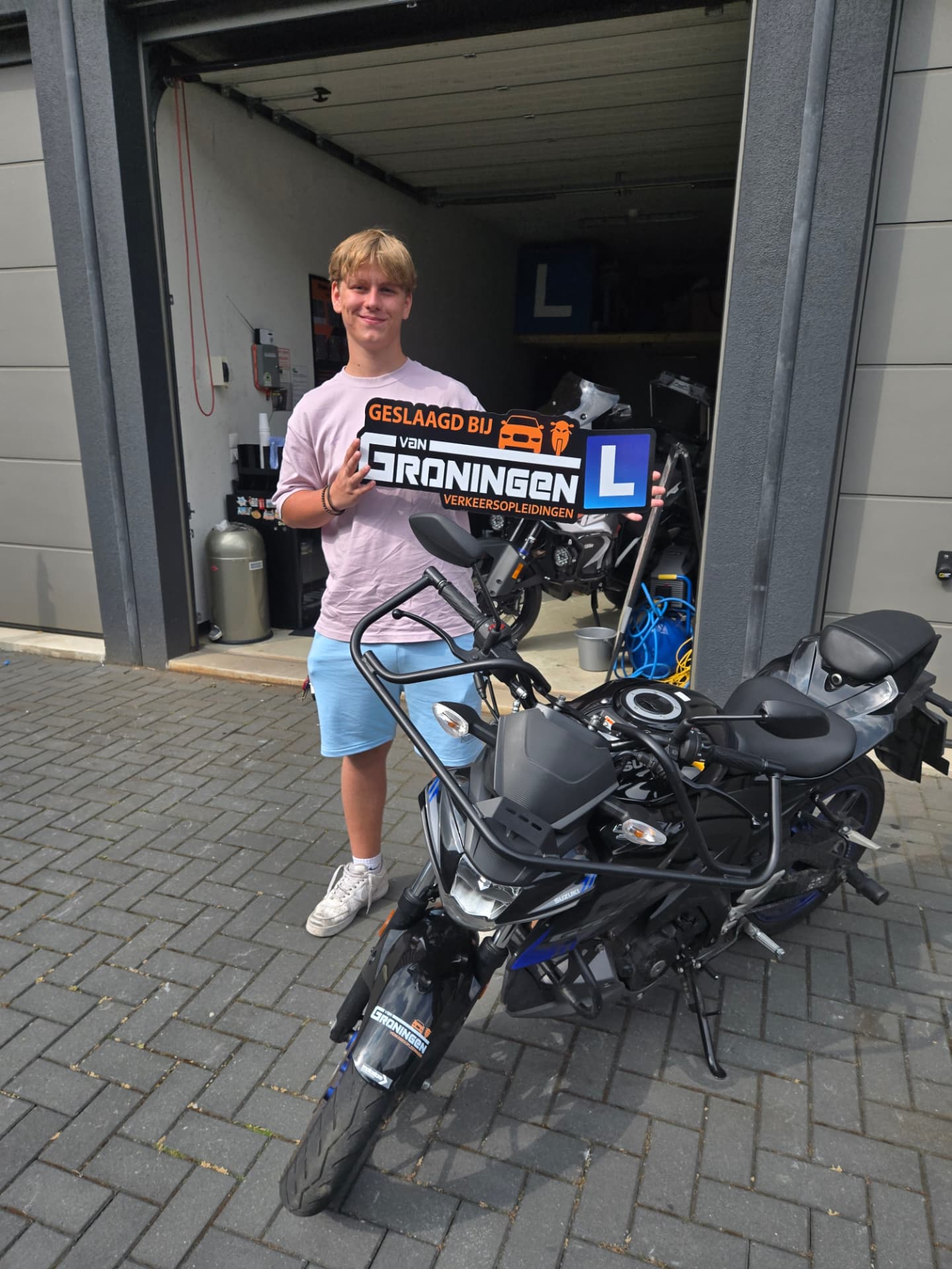 Geslaagde motorleerling naast de blauwe lesmotor